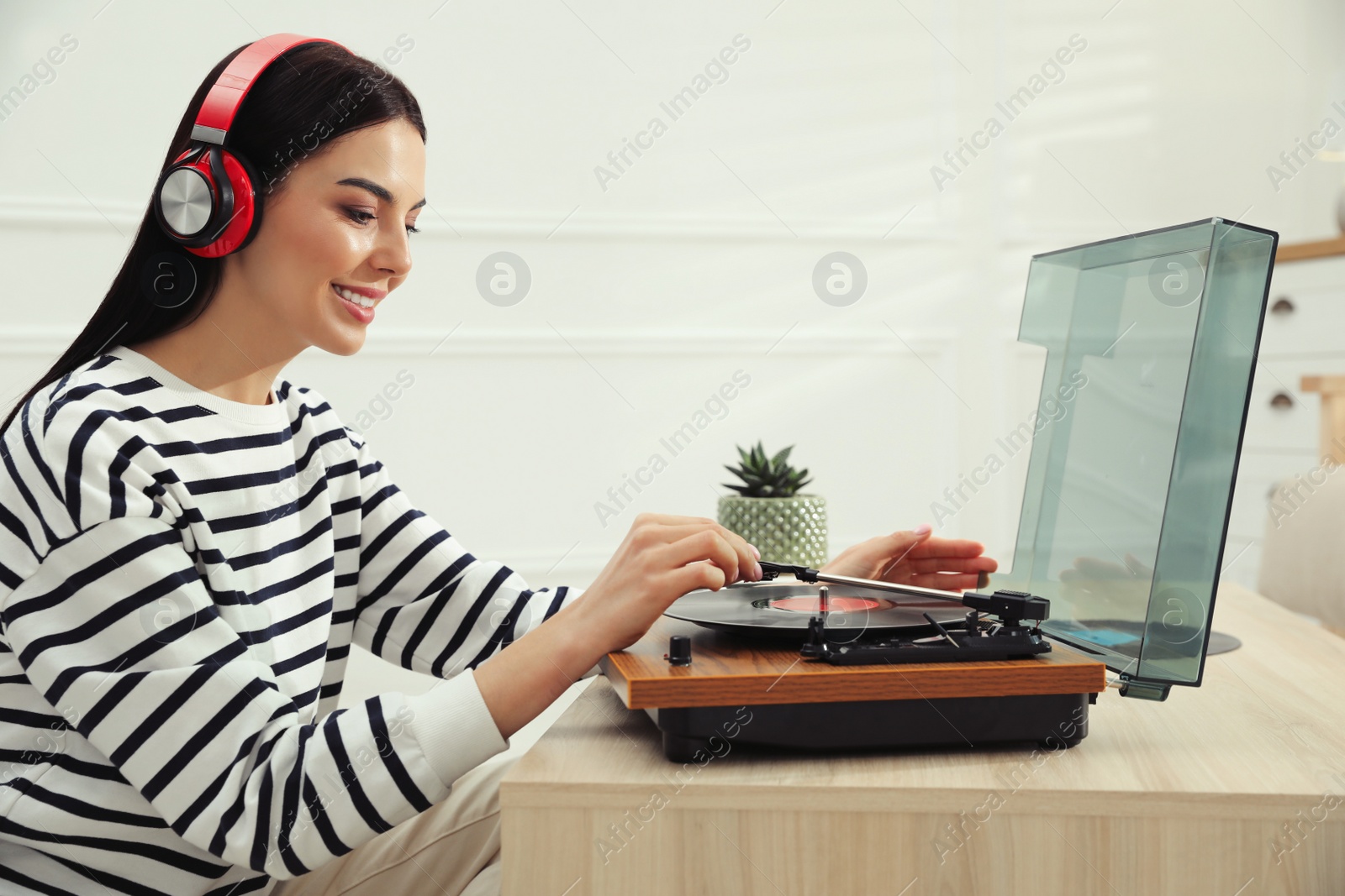 Photo of Woman listening to music with turntable at home