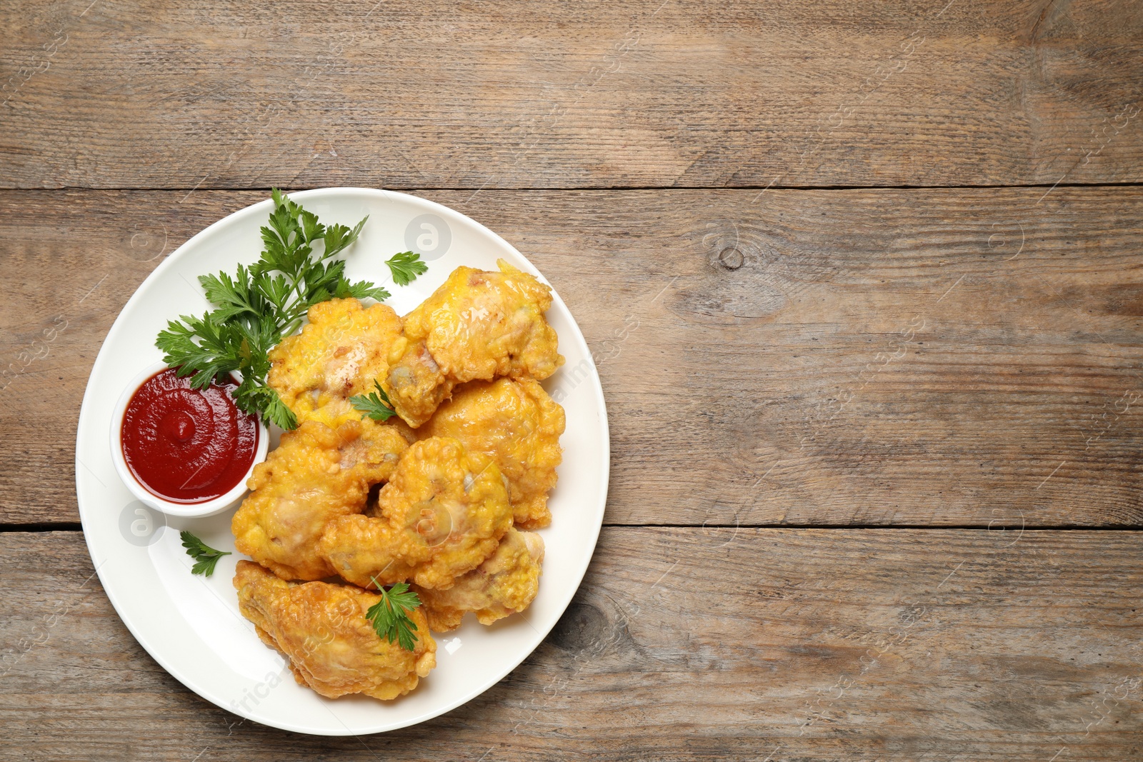 Photo of Tasty deep fried chicken pieces served on wooden table, top view. Space for text