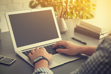 Image of Man working with laptop at table indoors, closeup. Space for design