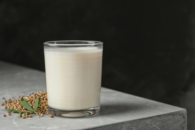 Photo of Composition with glass of hemp milk on grey table against dark background. Space for text