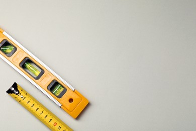 Building level and tape measure on beige background, top view. Space for text