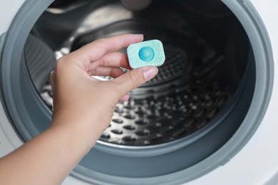 Photo of Woman putting water softener tablet into washing machine, closeup