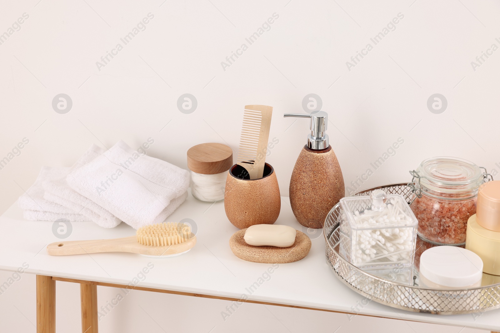 Photo of Different bath accessories and personal care products on table near white wall