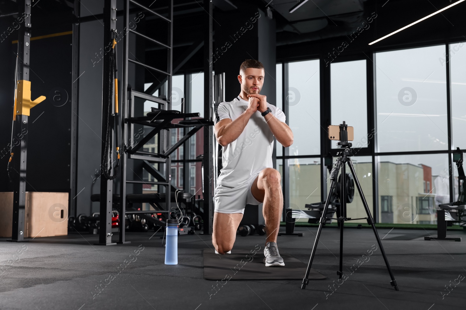 Photo of Trainer streaming online workout with phone at gym