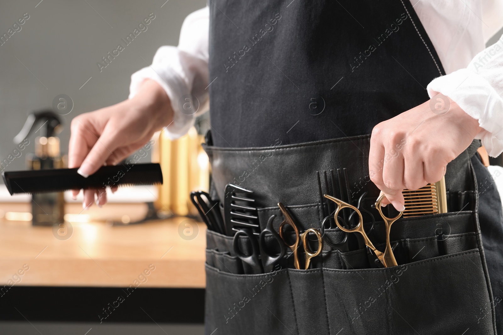 Photo of Hairstylist with professional tools in waist pouch in salon, closeup