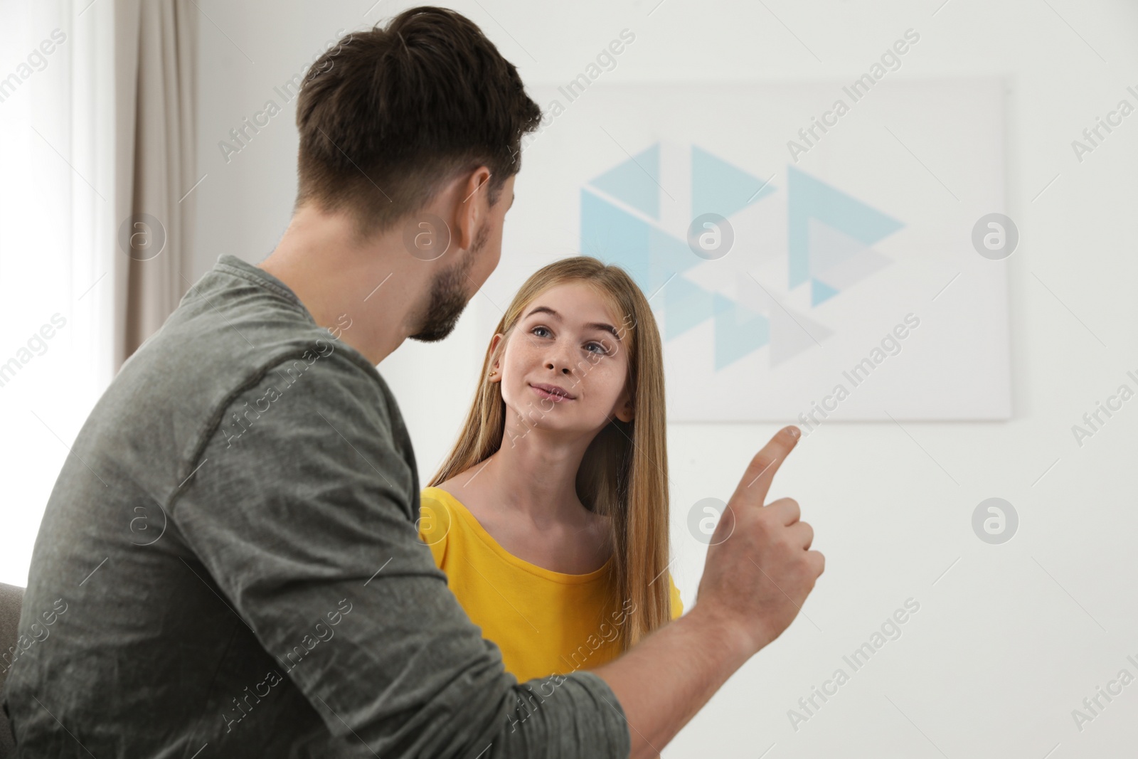 Photo of Father talking with his teenager daughter at home