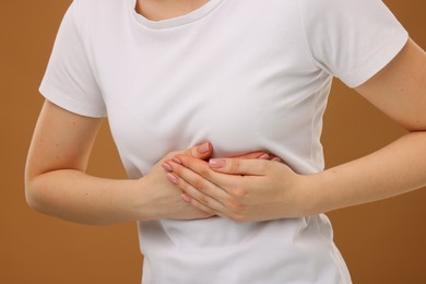Photo of Woman having heart attack on brown background, closeup