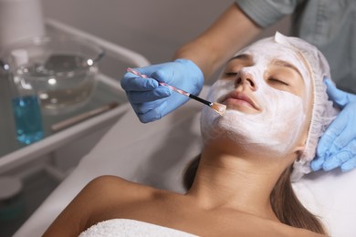 Photo of Cosmetologist applying mask on client's face in spa salon