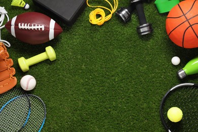 Different sport tools on green grass, flat lay. Space for text