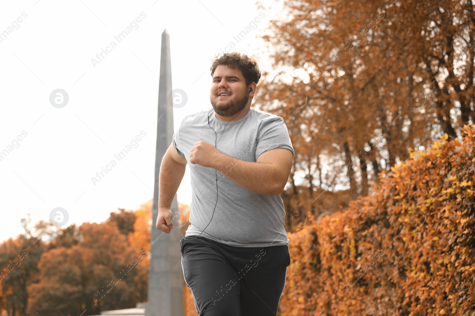 Photo of Young overweight man running in park. Fitness lifestyle