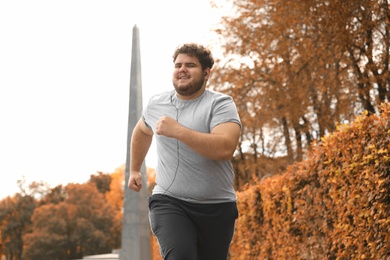 Young overweight man running in park. Fitness lifestyle
