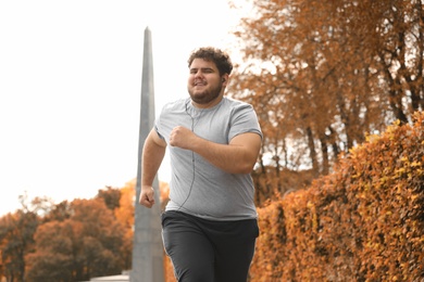 Photo of Young overweight man running in park. Fitness lifestyle