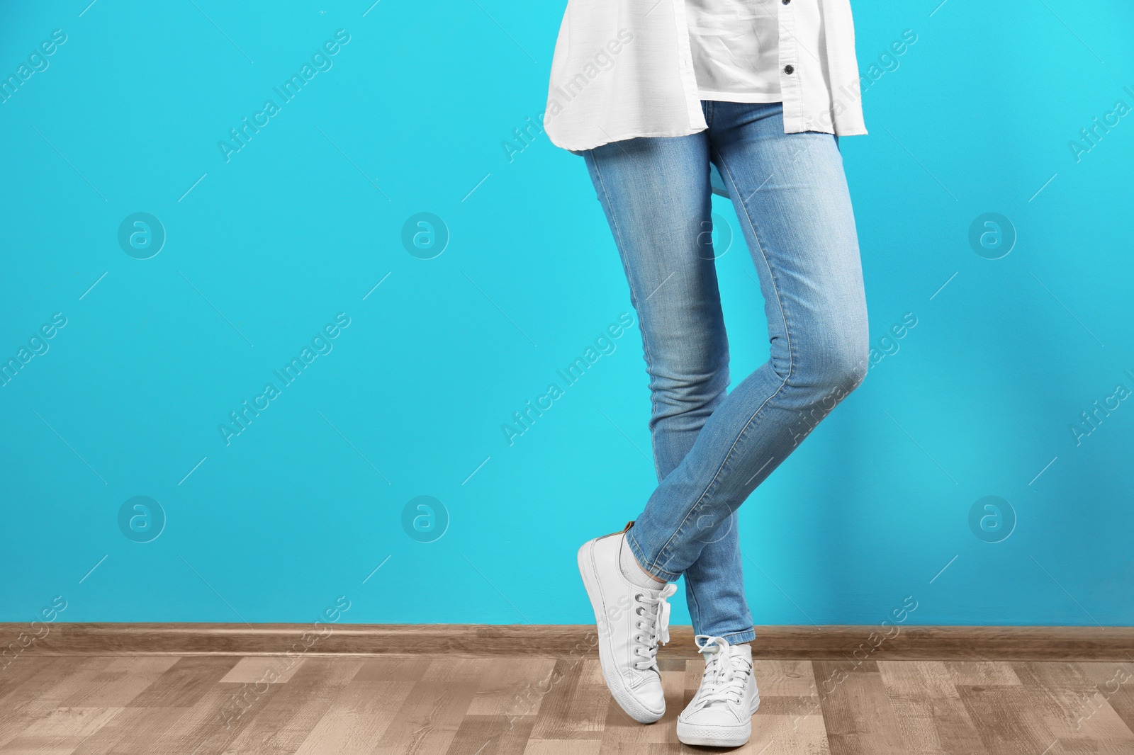 Photo of Young woman in stylish jeans near color wall