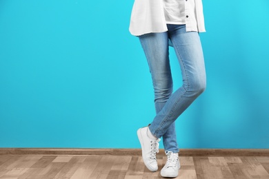 Young woman in stylish jeans near color wall