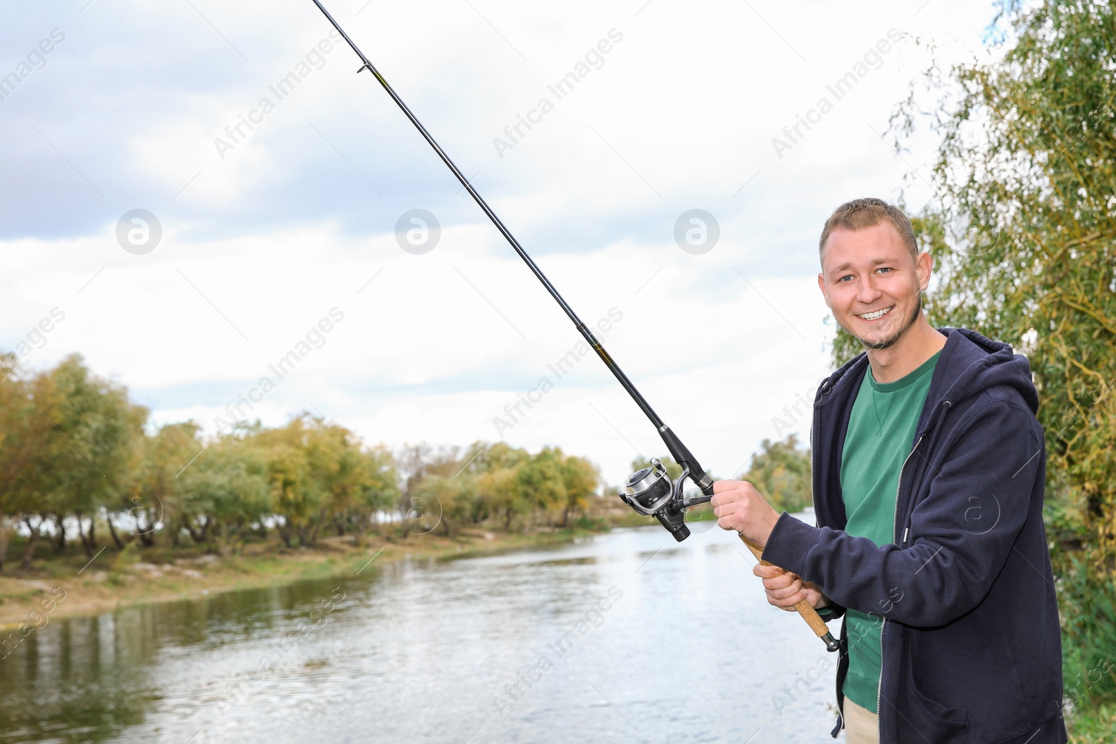 Photo of Man with rod fishing at riverside. Recreational activity