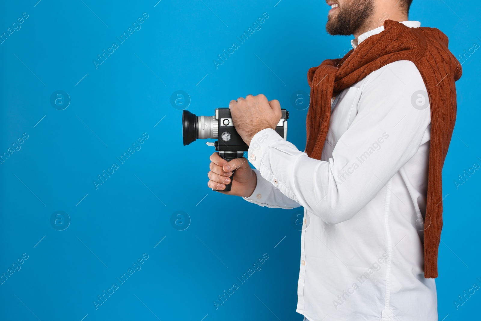 Photo of Man with vintage video camera on light blue background, closeup. Space for text