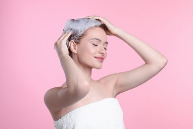 Photo of Happy young woman washing her hair with shampoo on pink background