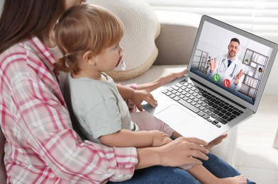 Image of Mother and daughter having online consultation with pediatrician via laptop on sofa at home