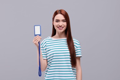 Young woman holding vip pass badge on light grey background