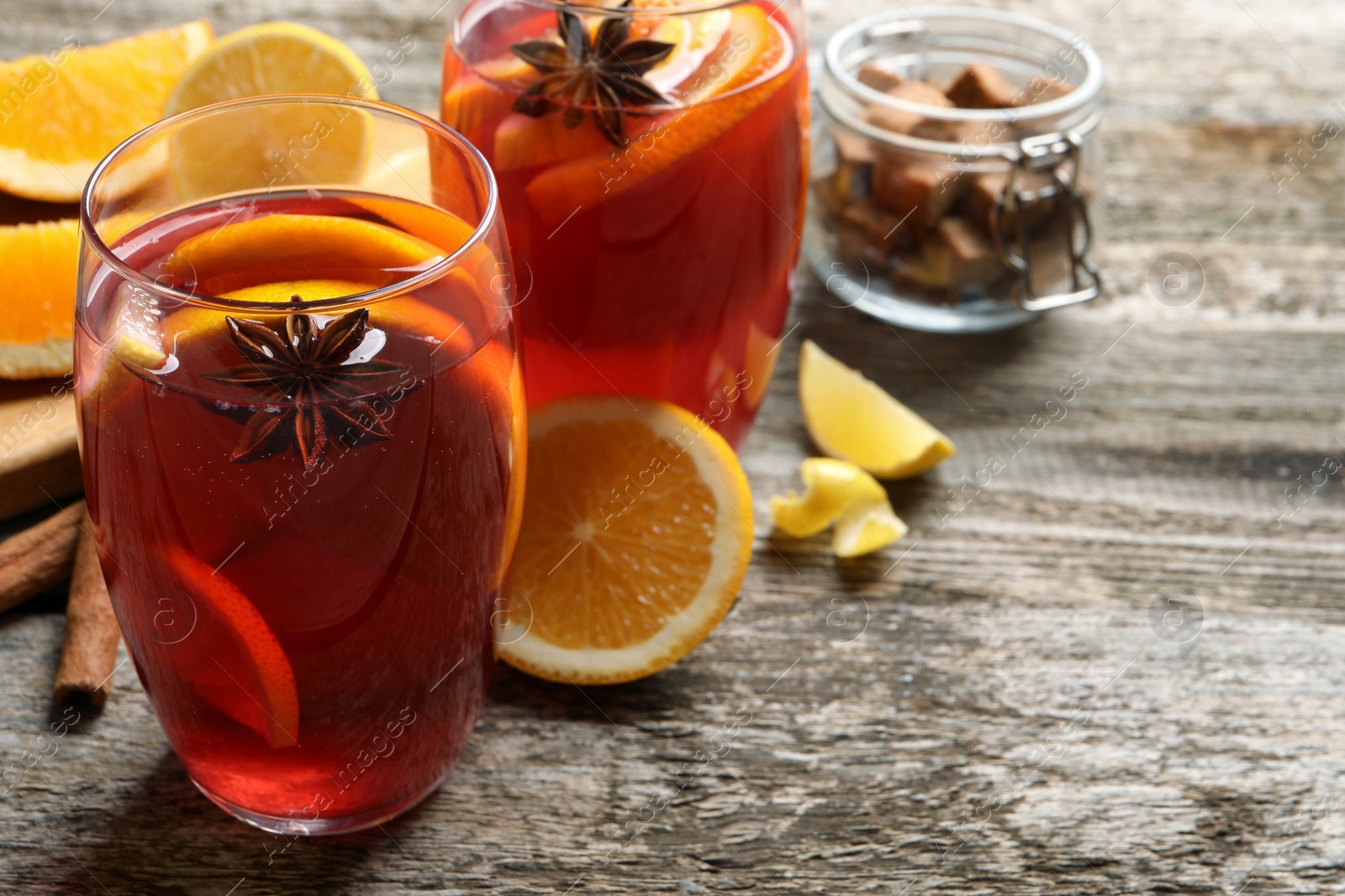 Photo of Aromatic punch drink and ingredients on wooden table. Space for text