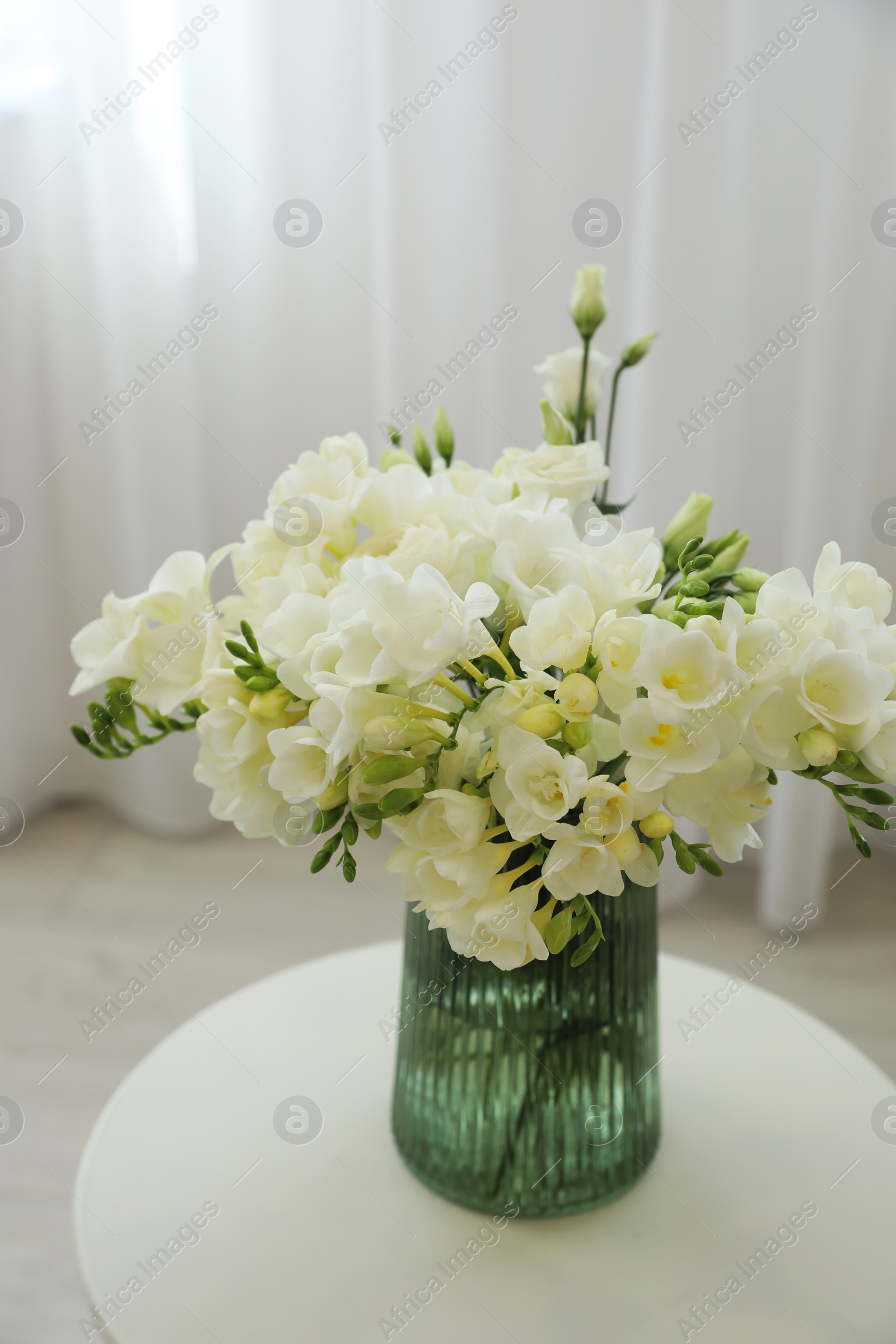 Photo of Beautiful bouquet with white freesia flowers on table indoors