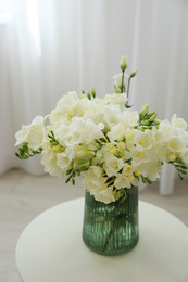 Beautiful bouquet with white freesia flowers on table indoors