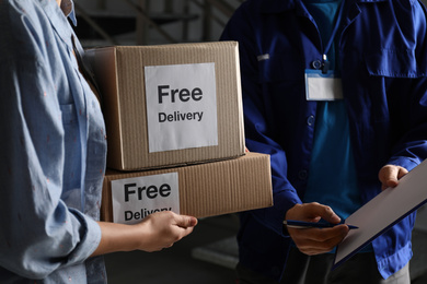 Photo of Woman receiving parcels from courier indoors, closeup