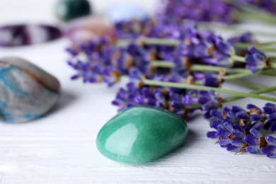 Photo of Gemstones and healing herbs on white wooden table, closeup