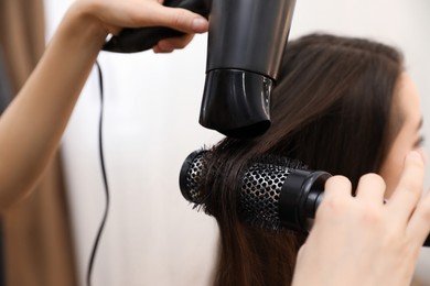 Photo of Stylist drying client's hair in beauty salon, closeup