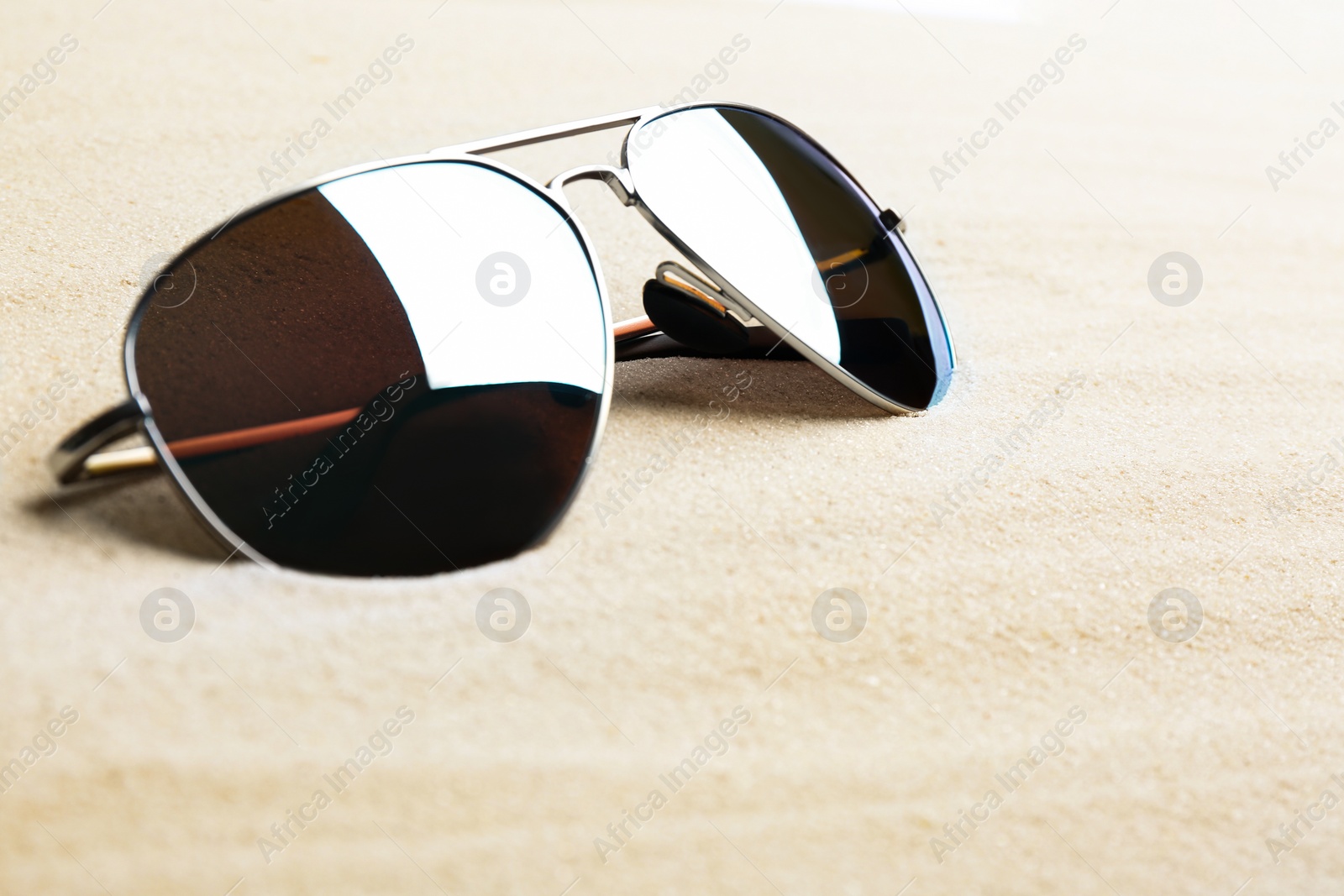 Photo of Stylish sunglasses on white sand, space for text. Summer time