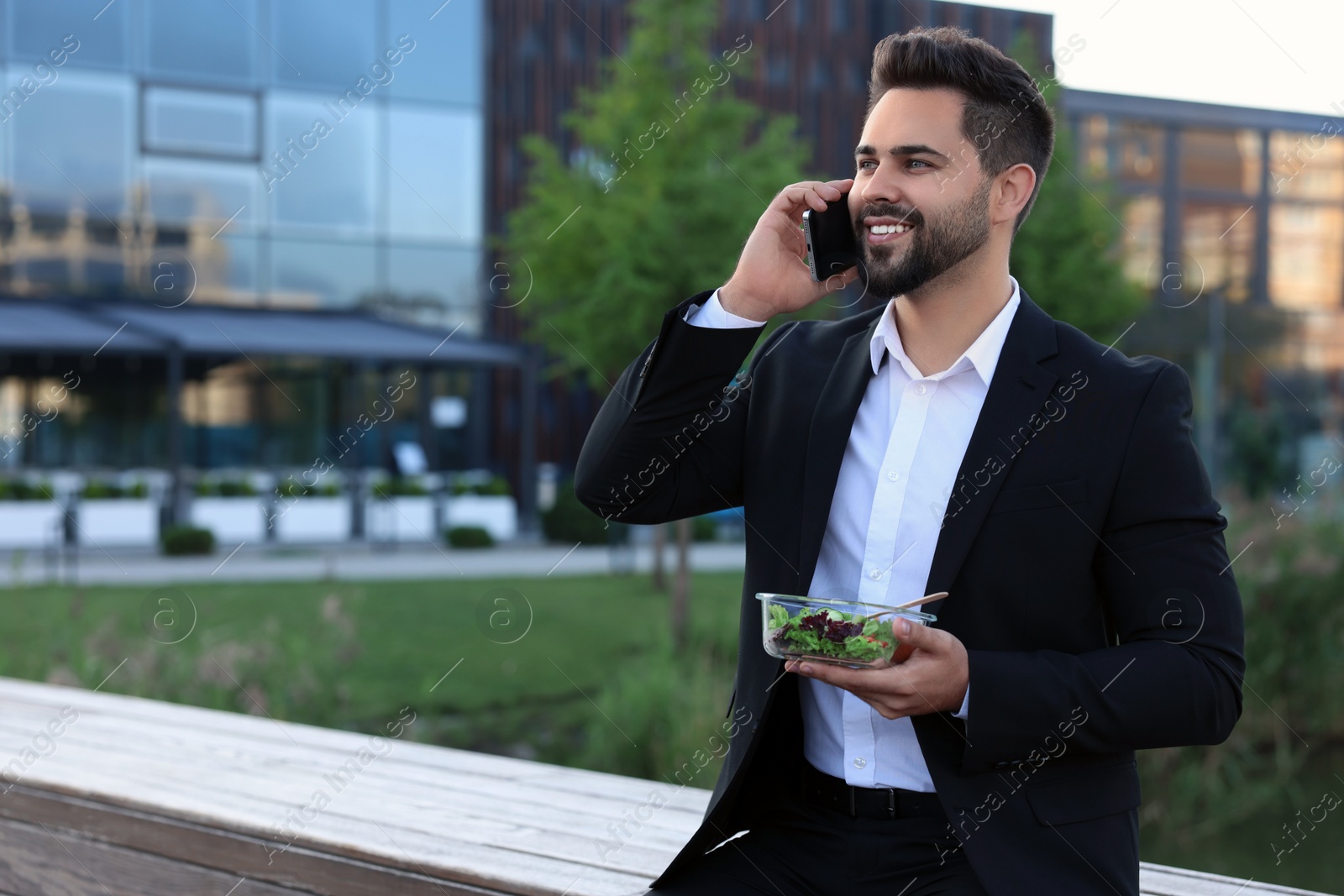 Photo of Smiling businessman talking by smartphone during lunch outdoors. Space for text