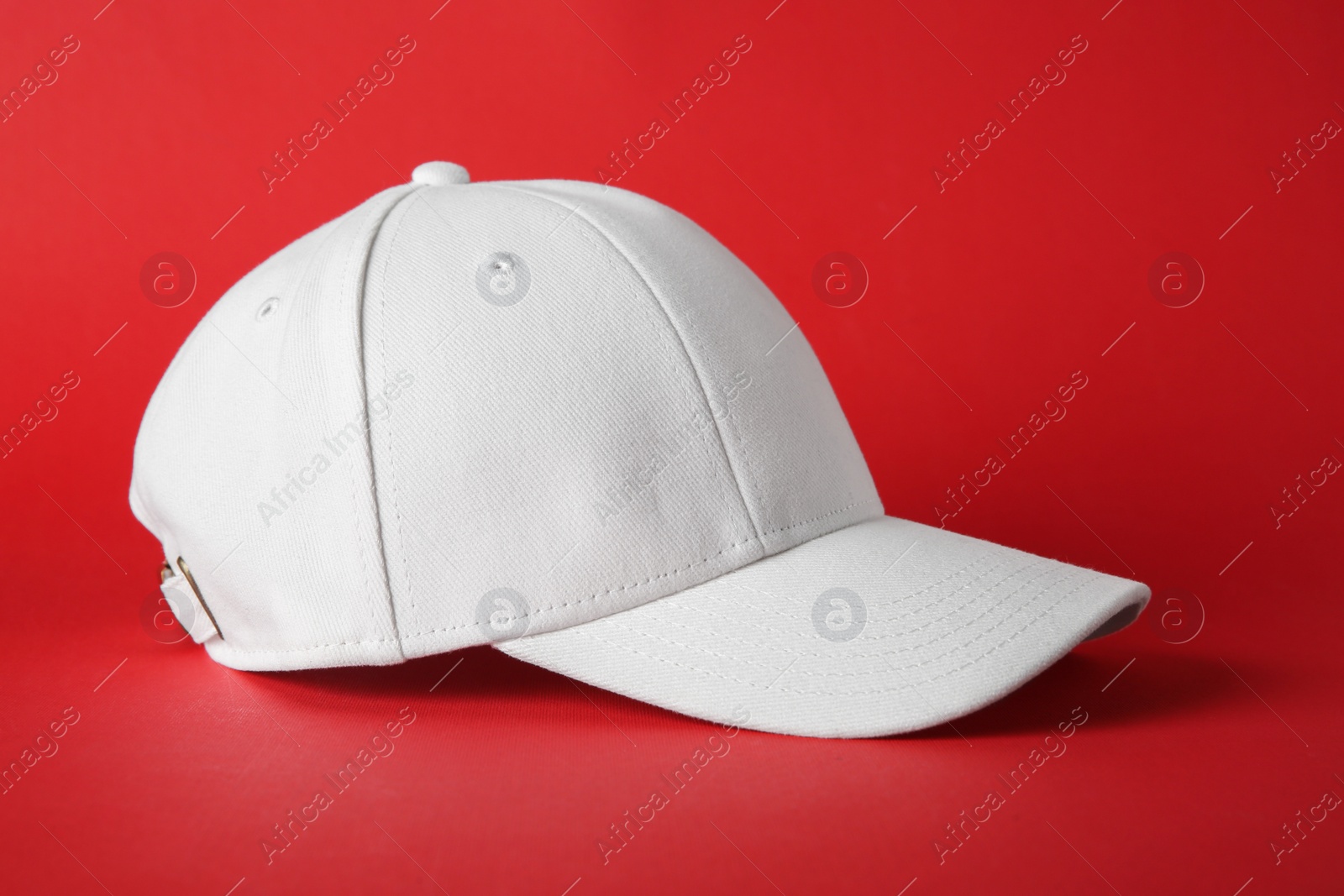 Photo of Stylish white baseball cap on red background