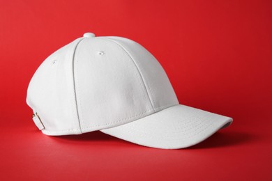 Stylish white baseball cap on red background