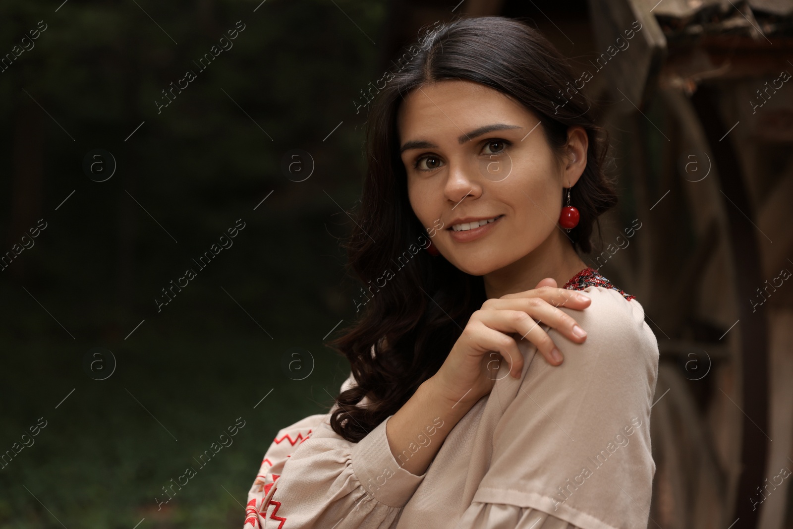 Photo of Beautiful woman wearing embroidered dress near old wooden well in countryside, space for text. Ukrainian national clothes