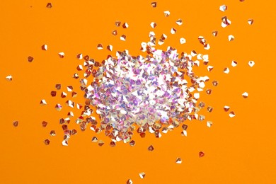 Photo of Pile of shiny glitter on orange background, flat lay