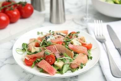Photo of Delicious pomelo salad with prosciutto served on white marble table