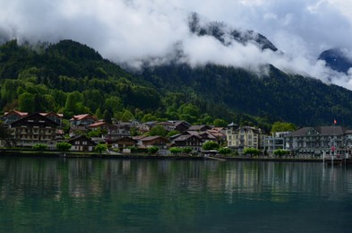 Photo of Picturesque view of beautiful village on lake shore near mountains