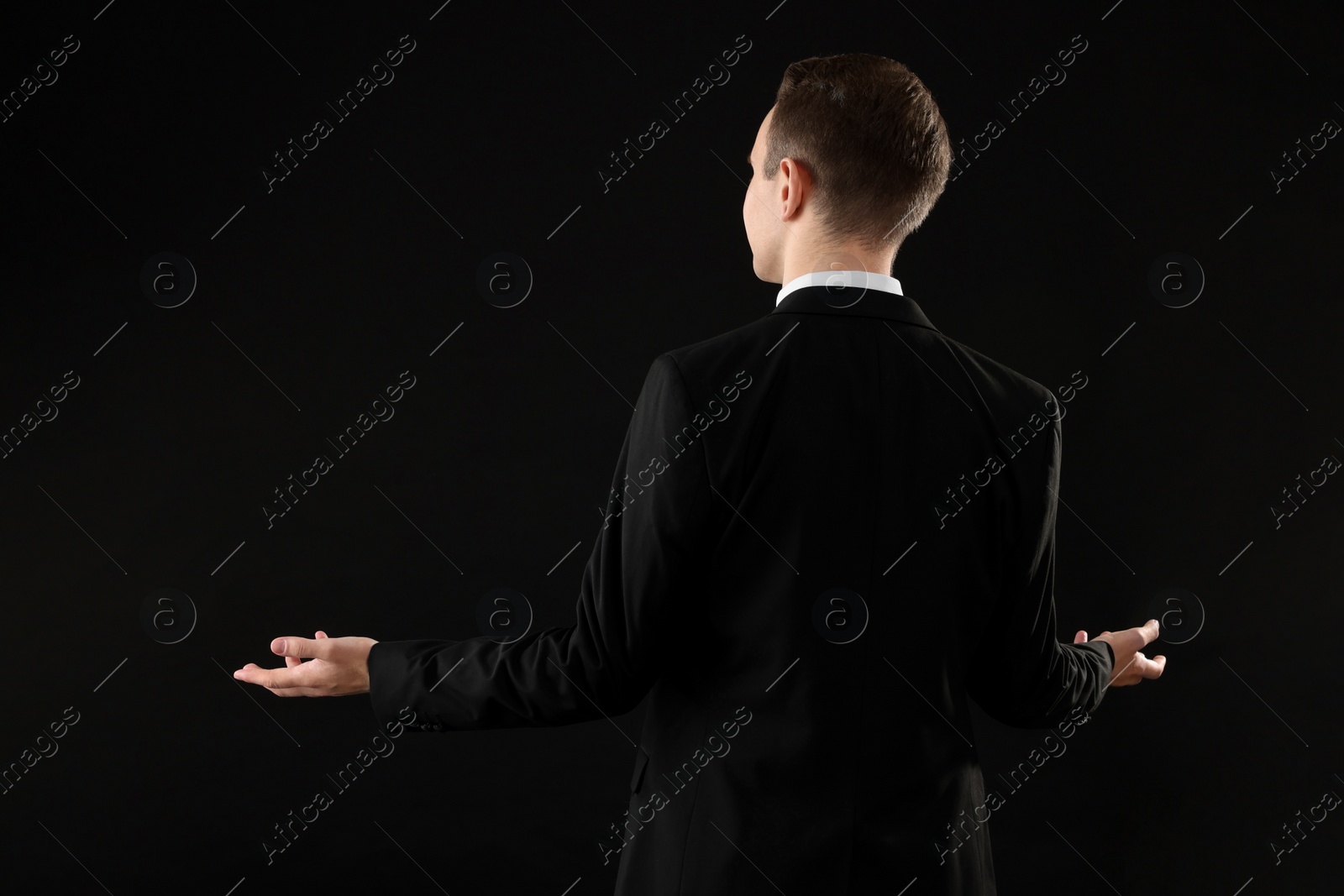 Photo of Man in suit on black background, back view