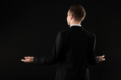 Photo of Man in suit on black background, back view