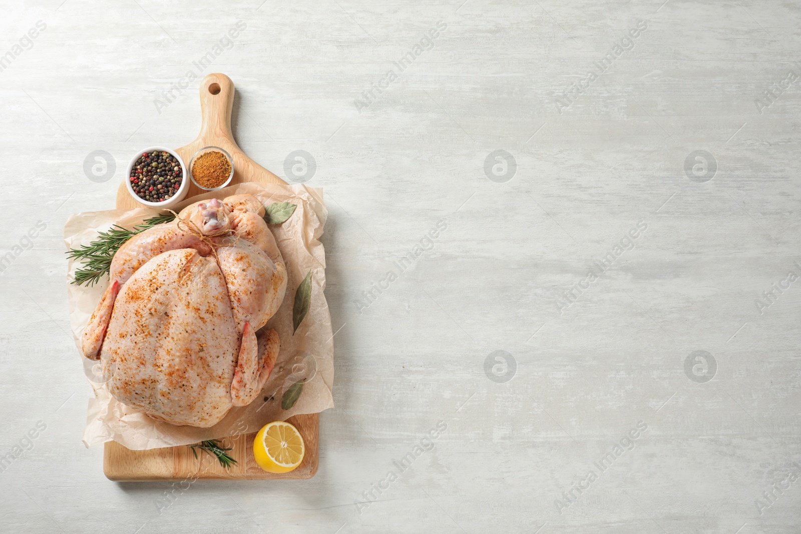 Photo of Board with raw spiced turkey and ingredients on light background, top view. Space for text