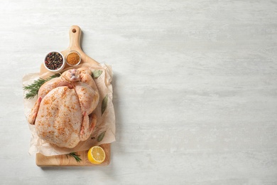 Board with raw spiced turkey and ingredients on light background, top view. Space for text