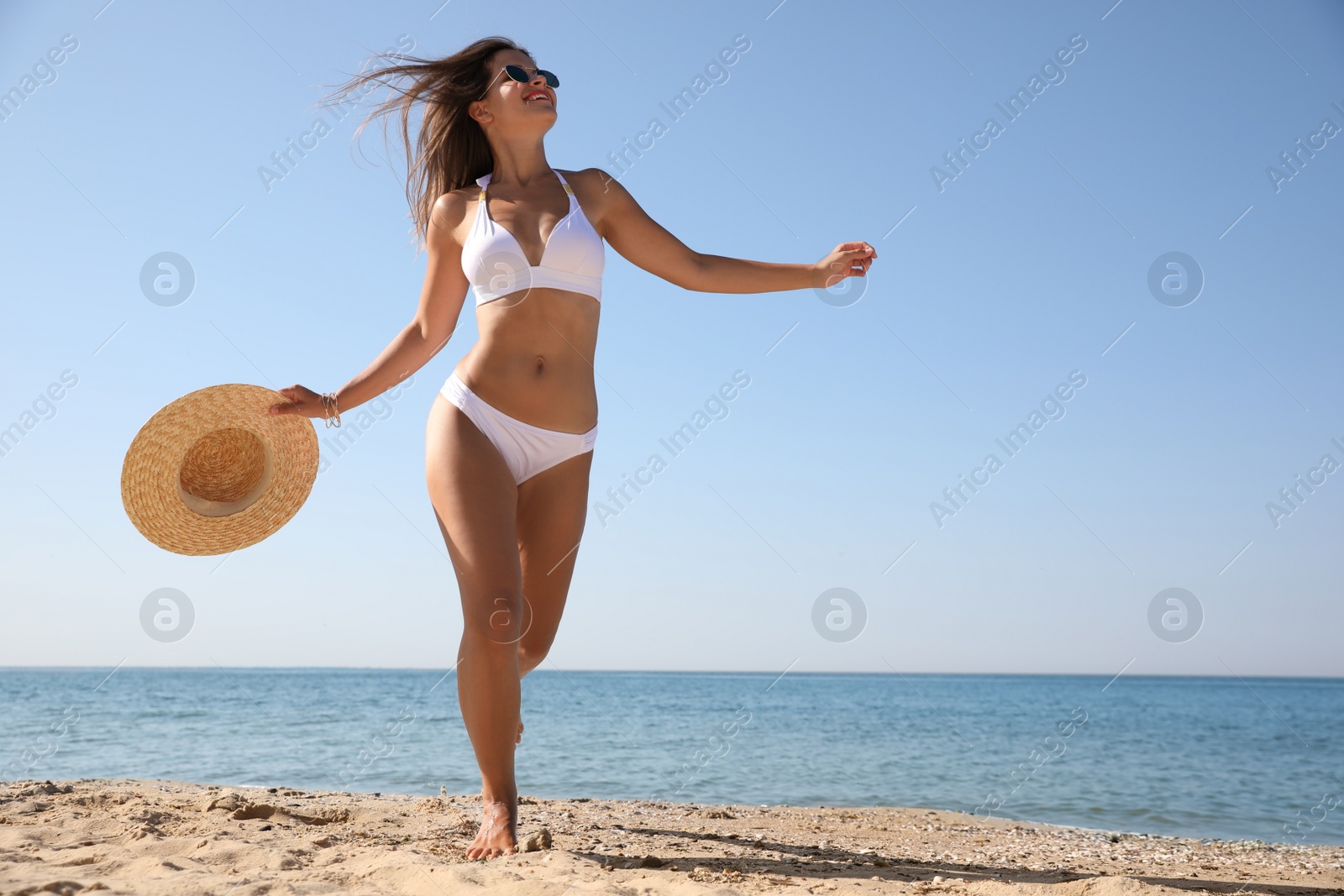 Photo of Young woman with beautiful body on sandy beach. Space for text