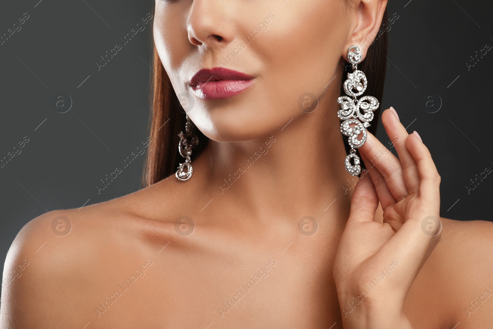 Photo of Beautiful young woman with elegant jewelry on dark background, closeup