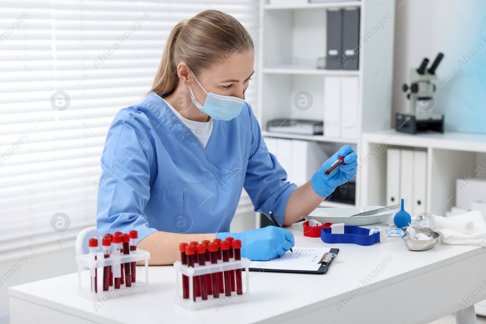 Photo of Laboratory testing. Doctor with blood samples in tubes at white table indoors