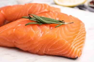 Photo of Marble board with tasty salmon fillet on table, closeup