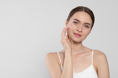 Young woman with cream around eye on white background, space for text