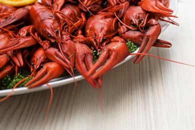 Photo of Plate with delicious red boiled crayfish on white wooden table, closeup