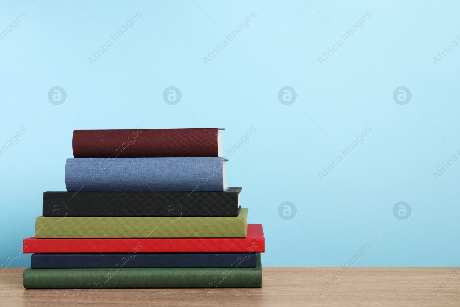 Photo of Stack of hardcover books on wooden table, space for text