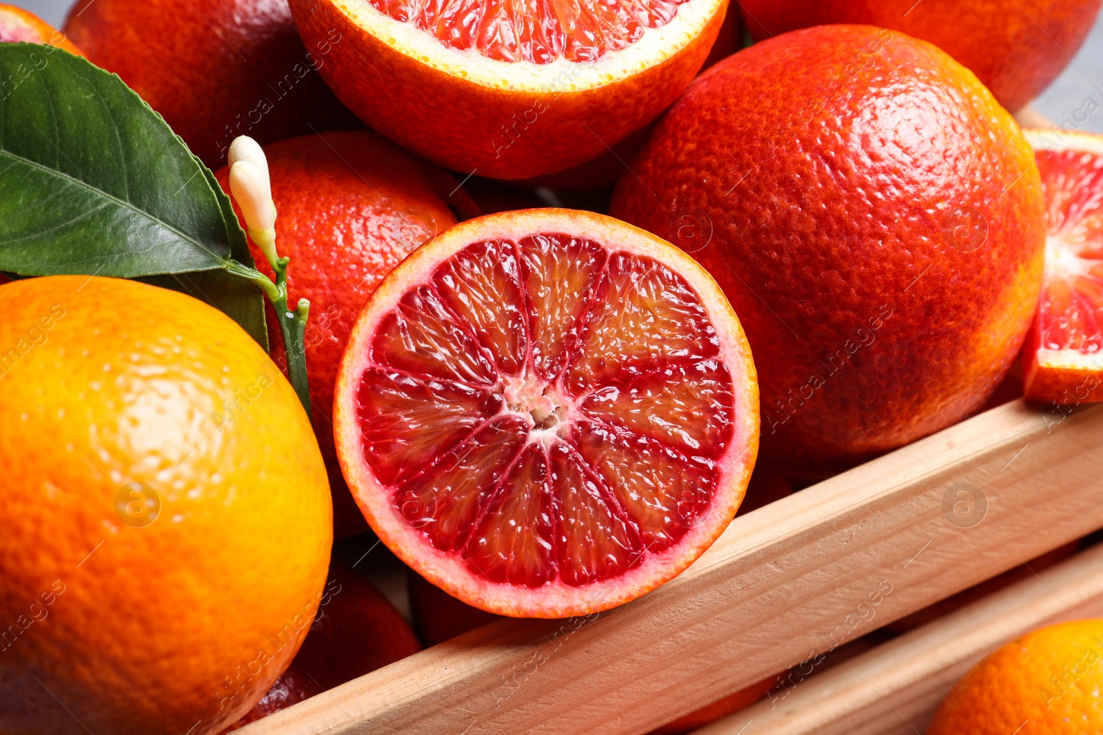 Photo of Ripe red oranges in wooden crate, closeup