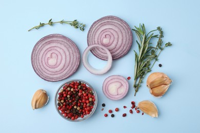 Fresh red onions, garlic, different herbs and spices on light blue background, flat lay